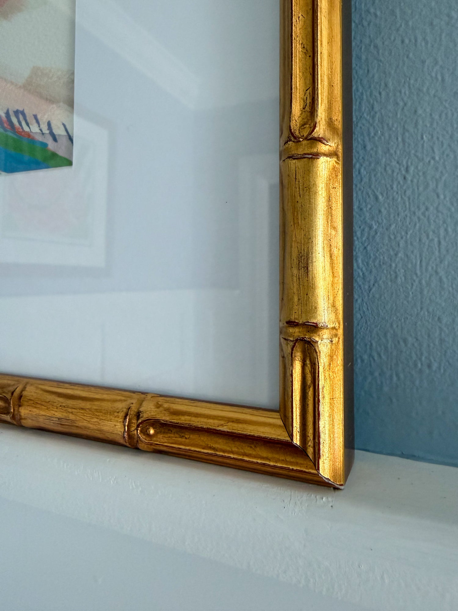 Gold picture frame corner on a white surface with a blue wall background
